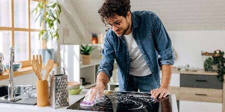 Homme nettoyant la plaque de cuisson avec un tampon de plaque de cuisson Scotch-Brite™
