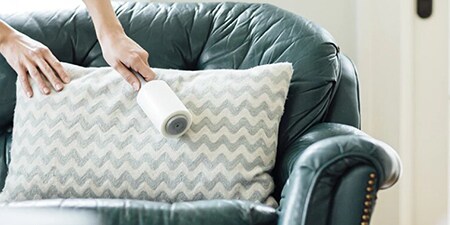 Femme en train de nettoyer un coussin avec un roulant anti-poussière Scotch-Brite™
