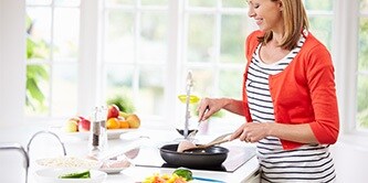 Un femme en train de cuisiner sur une plaque de cuisson
