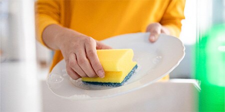 Femme faisant la vaisselle avec l’éponge grattante Scotch-Brite® Delicate Nail Saver
