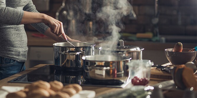 Une femme en train de préparer un repas dans trois casseroles
